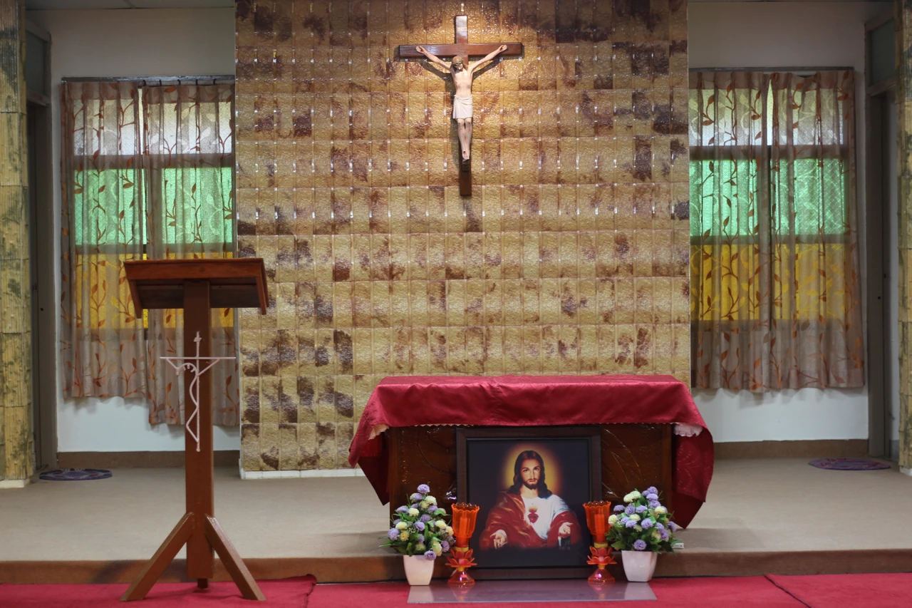 The chapel's altar and crucifix between stained-glass windows.