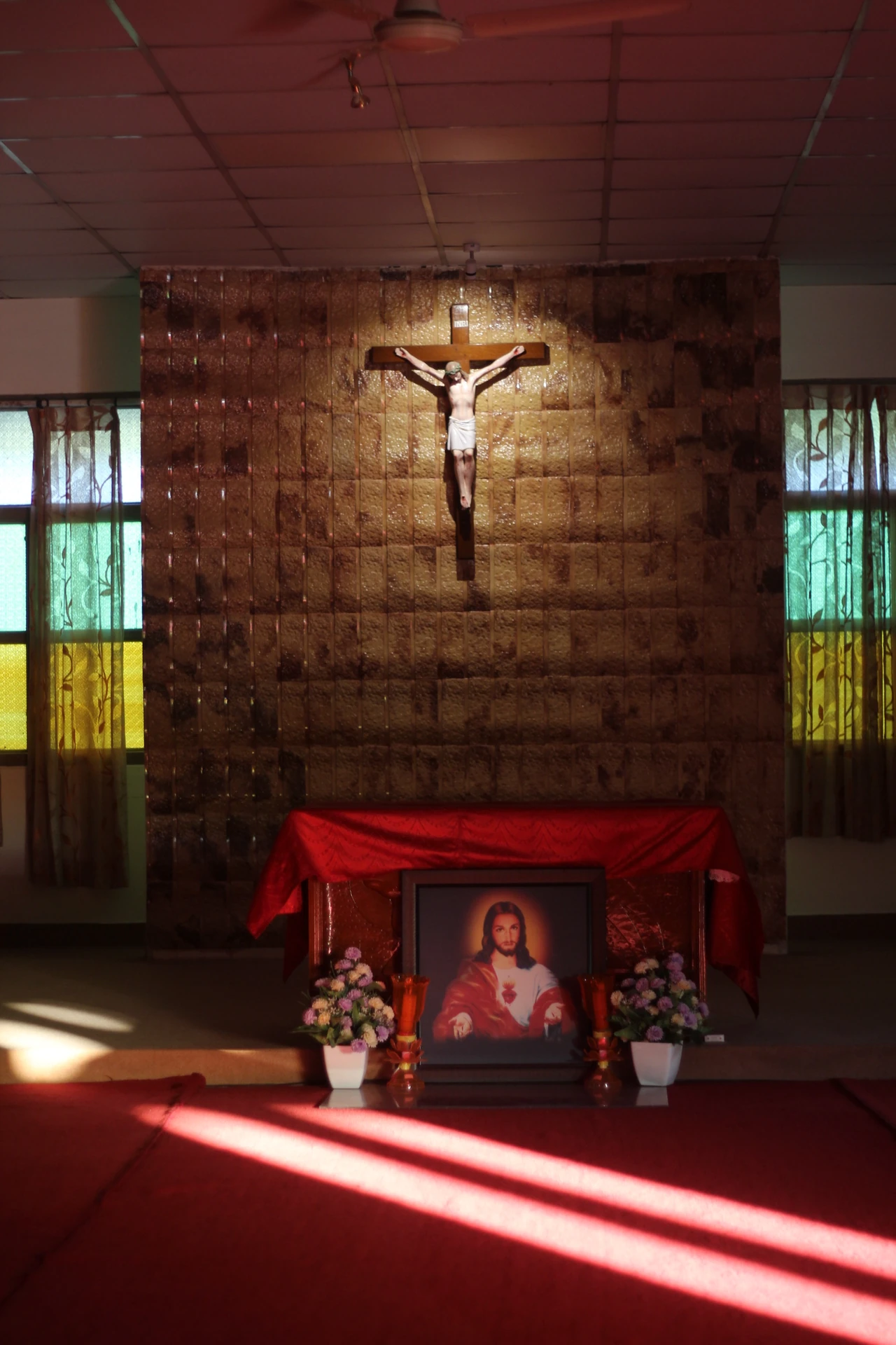 A side view of the crucifix and altar, with sunlight entering the chapel.