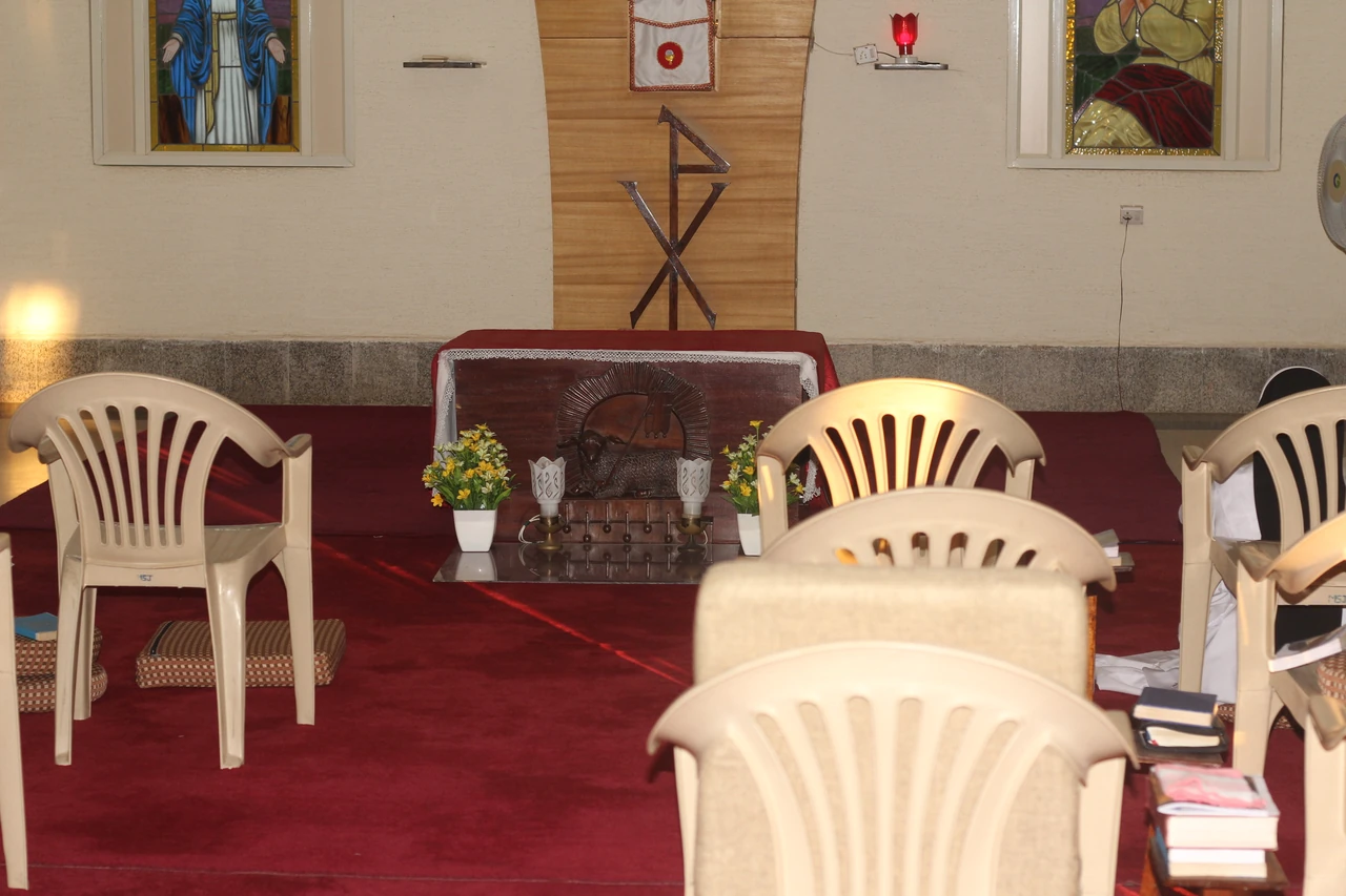 Chairs facing a small altar and crucifix in a quiet prayer room.