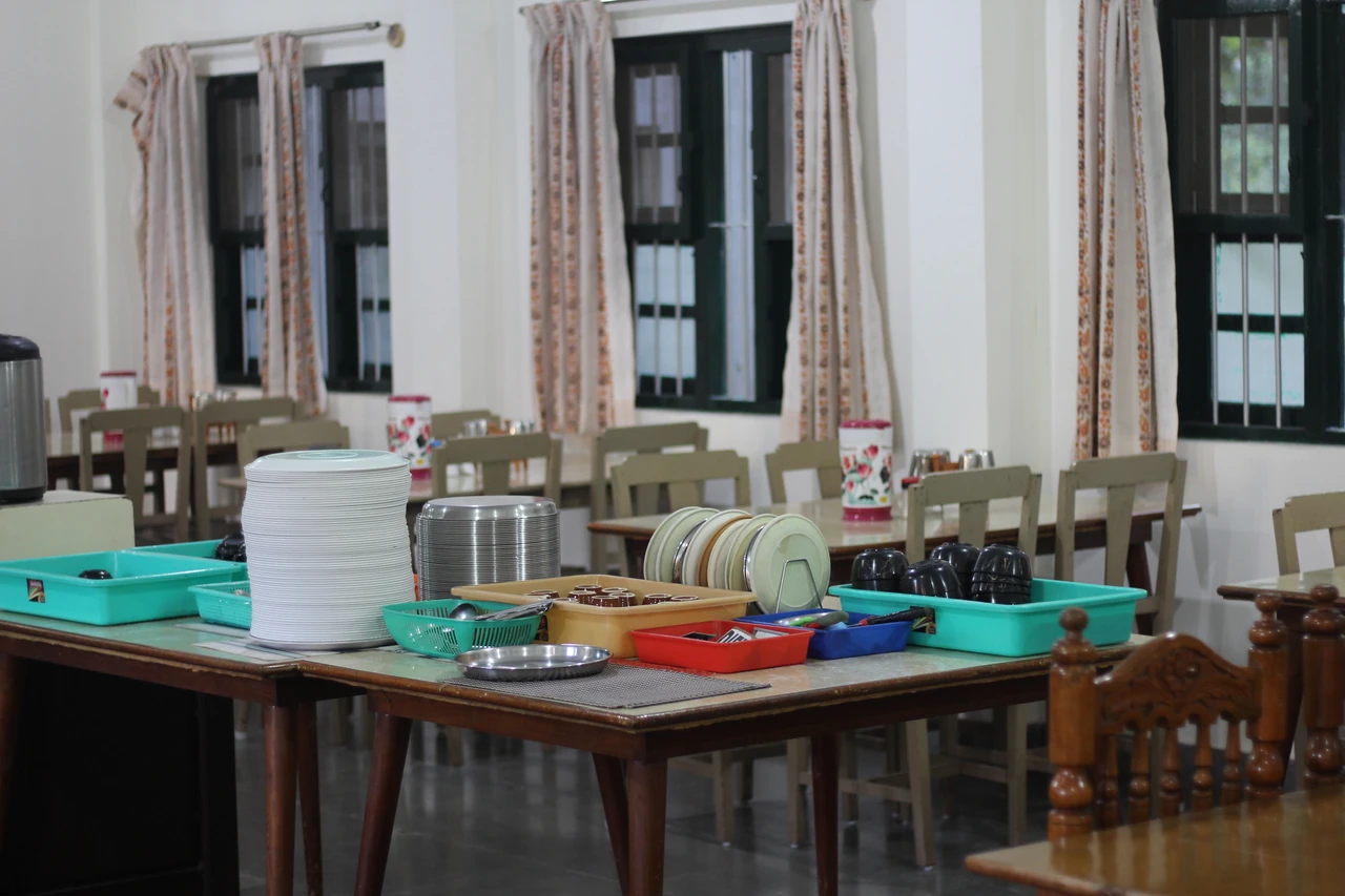 Serving dishes and water jugs arranged on a dining-hall table.