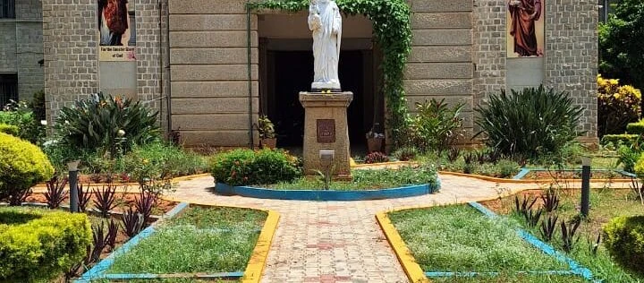 A white statue surrounded by a small planted garden beside the retreat house.